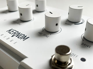 Photo of the Kernom RIDGE overdrive, a white overdrive pedal. The focus is made on the PRE TONE knob